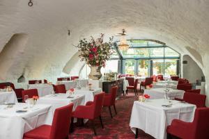 芬洛彼尔德伯格酒店的用餐室配有白色的桌子和红色的椅子