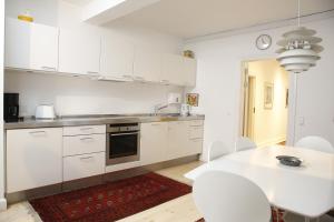 哥本哈根哥本哈根公寓的厨房配有白色橱柜和桌椅