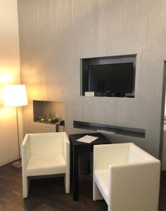贝德堡古特霍恩霍尔斯酒店的客厅配有桌子、两把椅子和电视