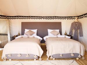 El GoueraNubia Luxury Camp Erg Chegaga的一间帐篷内带两张床的卧室