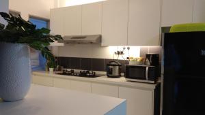 新山INFA@新山赛罗亚公寓的厨房配有白色橱柜和微波炉