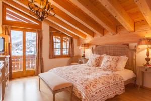 采尔马特Vrony Apartments by Hotel Walliserhof Zermatt的一间带一张床的卧室,位于带木制天花板的房间内