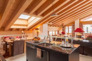采尔马特Vrony Apartments by Hotel Walliserhof Zermatt的一间带大岛的厨房,位于一间设有木制天花板的客房