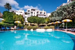 伊斯基亚乌丽赛酒店的一座带遮阳伞的大型游泳池,周围的人可以围着游泳池
