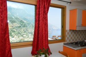 波西塔诺La Casarella Apartment Positano的厨房设有2扇带红色窗帘的大窗户