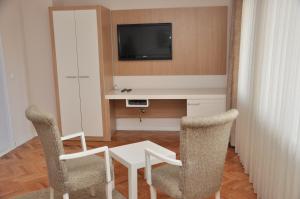 普里什蒂纳普瑞玛酒店的配有桌子和两把椅子以及电视的房间