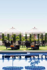 清迈清迈苏瑞旺斯酒店的一个带桌椅和遮阳伞的游泳池