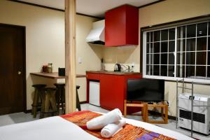 饭山市高原斑尾旅馆的一间设有一张床的客房和一间带红色橱柜的厨房