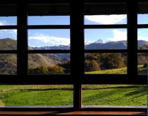 ToríoLa Casona de Torió的从田野和山脉的窗户欣赏美景