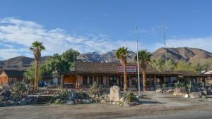 Panamint SpringsPanamint Springs Motel & Tents的一座棕榈树和山脉环绕的建筑