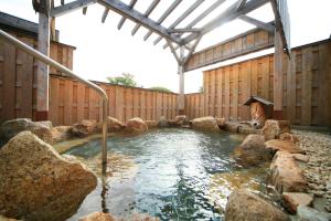 奈良米卡萨酒店 的木制建筑中带岩石的热水浴池
