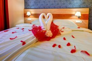利波瓦拉尼Hotel Toč的两个穿红色衣服的天鹅坐在床上