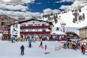 上陶恩Austria Alpinhotel的一群人在滑雪小屋前滑雪