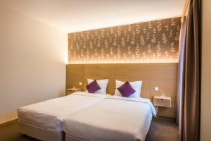 Scheidgen邦瑞珀斯酒店的卧室配有一张带紫色枕头的大型白色床。