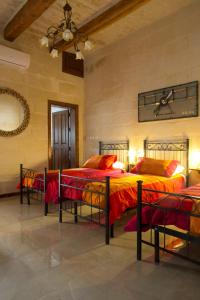 斯利马Maltese Town House Sliema的一间卧室配有3张红色和橙色床单