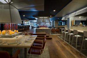 夏蒙尼-勃朗峰Heliopic Hotel & Spa的一间带桌椅的餐厅和一间酒吧