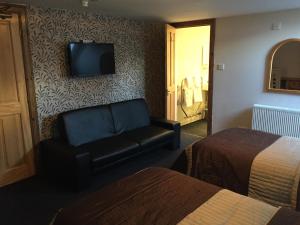 Bridgend of LintrathenLodge at Lochside的酒店客房设有沙发,墙上配有电视。