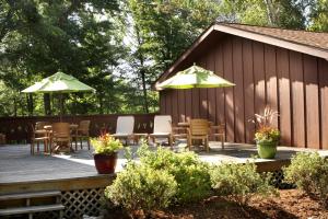 伊格尔里弗Lake Forest Resort的一个带桌椅和遮阳伞的木制甲板