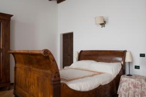 PodenzanoPalazzo Turro Bed & Breakfast的一间卧室配有一张带白色床单的旧木床。