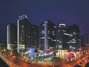 杭州杭州奥克伍德国际酒店公寓 - 近西湖，比邻黄龙体育中心的城市中一座大建筑的夜景