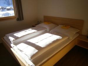 布雷根茨沃尔德地区奥Haus Zitterklapfen的一张带两张白色床单和窗户的床