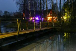 VecslavēkasGuest House Vējaines的夜晚在河前有灯的房子