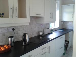 CarrigallenBridgefield House的厨房配有白色橱柜和黑色台面