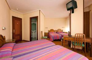 纳赫拉希斯潘诺旅馆的一间卧室配有两张床、一张桌子和一台电视。