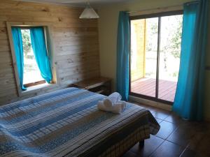 科克拉内Cabañas Rincon del Sur的一间卧室配有一张带蓝色窗帘的床和甲板