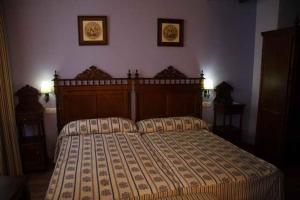 韦斯卡尔Hotel El Maño的一间卧室配有一张大床,墙上有两张照片