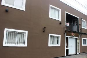 皮拉尔Complejo Kalifornia的棕色的建筑,设有白色的窗户和阳台