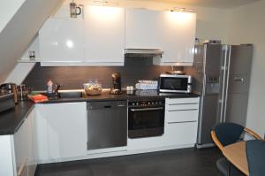 埃森Ferienwohnung "Haus 10"的厨房配有白色橱柜和不锈钢冰箱