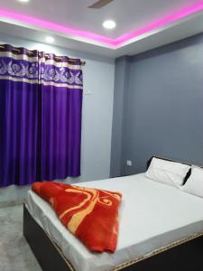 加雅Hotel Sunaina International的一间卧室配有一张带紫色窗帘的床