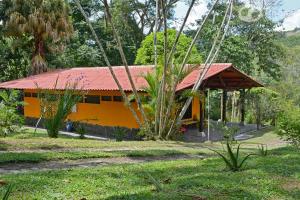 La ManuelitaTinamu Birding的黄色的房屋,有红色的屋顶