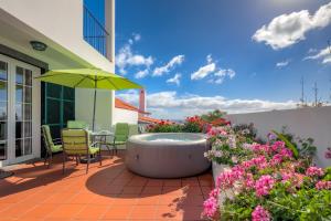 卡尼索Villa Atalaia by HR Madeira的庭院设有热水浴池、椅子和鲜花