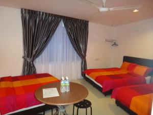 马六甲法摩萨2号民宿的配有桌子和窗户的客房内的两张床