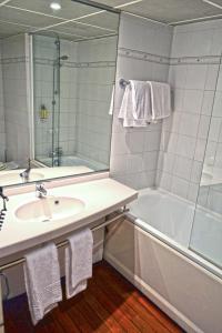 庞坦巴黎艺术酒店 的一间带水槽、浴缸和镜子的浴室