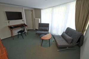 慕尼黑Parkhotel Obermenzing的客厅配有两把椅子、一台电视和一张桌子