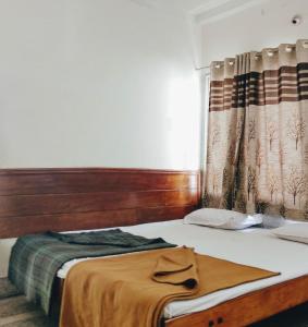 迈索尔Hotel Ashwini Lodge的一间卧室配有一张带木制床头板的床和窗户。
