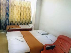 迈索尔Hotel Ashwini Lodge的配有红色椅子的客房内的两张床