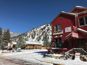 红河The Lodge at Red River的雪中一座红色的建筑,有山