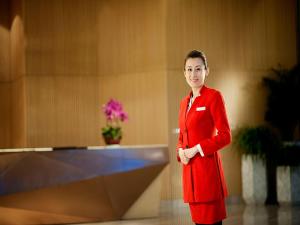 黄岛青岛银沙滩温德姆至尊酒店的身着红色西装的女人站在房间里