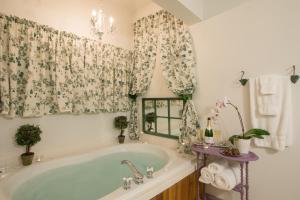 卡南代瓜苏特兰维多利亚式住宿加早餐旅馆的带浴缸的浴室和带窗帘的窗户