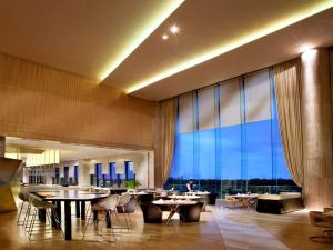 黄岛青岛银沙滩温德姆至尊酒店的餐厅设有桌椅和大窗户。