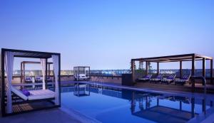 迪拜普尔曼迪拜河城市中心酒店的一座带椅子的游泳池以及一座楼顶的凉亭