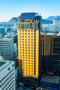 首尔南大门伊娜套房酒店的一座黄色的建筑,上面有城市的标志