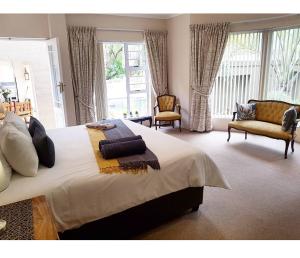 奥茨胡恩Oudtshoorn Guest House的一间卧室配有一张大床和两把椅子