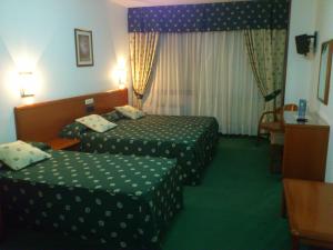 帕德隆斯卡拉酒店的酒店客房设有两张床和一张桌子。