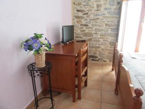 NocecoHotel rural Valtarranz的一间卧室配有一张桌子、一台电视和鲜花