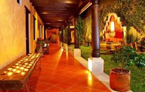 危地马拉安地瓜Hotel Meson del Valle by AHS的走廊上设有长凳和植物的建筑